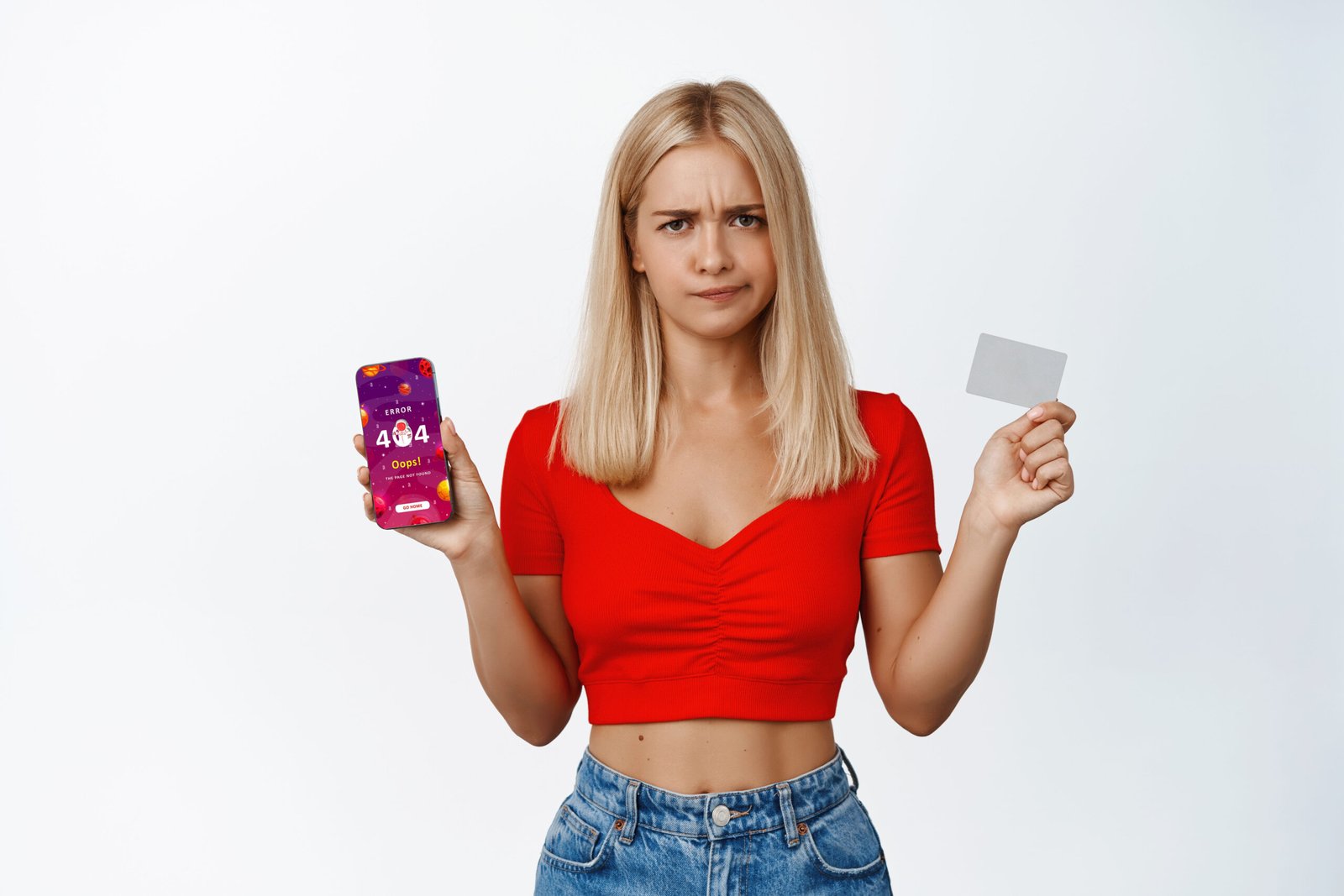 Displeased blond girl grimaces, shows mobile phone screen and credit card, pouting upset, standing over white background